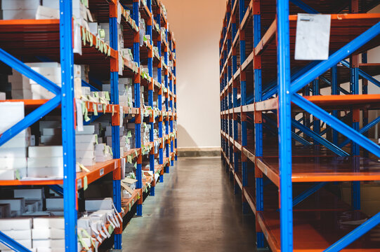 Warehouse storage shelf aisle inventory logistics industry distribution organization stock warehouse aisle with orange and blue metal shelf full of white box inventory creating organized storage