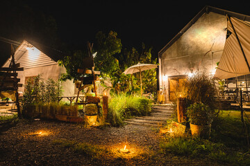 Fototapeta premium Camp party outdoor holiday relax atmosphere with warm lighting rustic building garden path and cozy night setting create peaceful retreat for friends to unwind and enjoy nature together