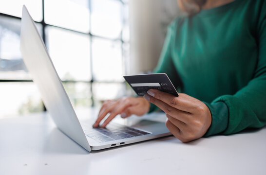 A person engages in online shopping using a laptop and credit card, showcasing modern technology and consumer behavior.