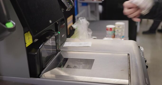 Woman scanning canned cat food at self checkout machine in supermarket