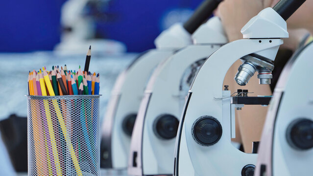 Microscopes and colorful pencils lining a table for science education and discovery