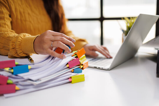 This engaging image features a person managing papers with colorful sticky notes around a laptop, reflecting a detailed planning process and systematic approach.