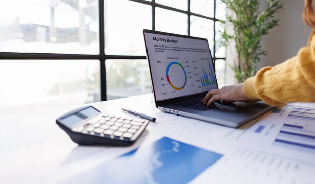 An insightful view of a laptop screen displaying a monthly budget overview accompanied by colorful graphs that illustrate spending patterns and financial insights within an organized space.