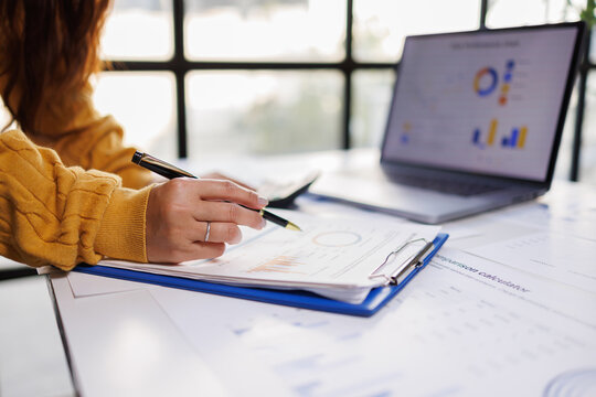 An individual meticulously reviewing business documents in a modern office setting, highlighting the importance of attention to detail and productivity in professional environments.