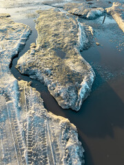 Fototapeta premium A puddle of melt water on a frozen road as a background