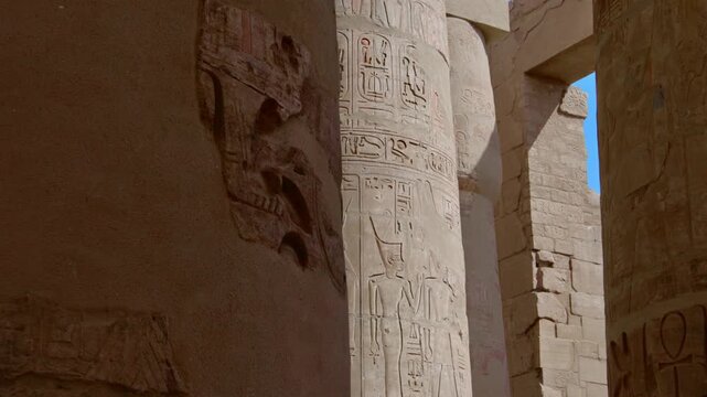 Karnak Temple in Luxor, Egypt. Massive hieroglyphic columns in Great Hypostyle Hall, Karnak Temple Luxor Egypt. Upward view of ancient carved pillars against blue sky.