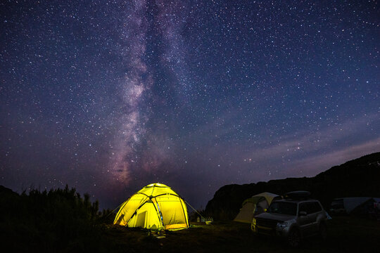Tourist camping near the sea under the night sky with milky way.