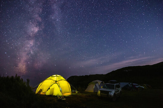 Tourist camping near the sea under the night sky with milky way.