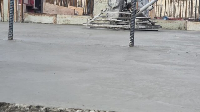 Slow motion close up of rotating power trowel blades finishing fresh concrete surface.