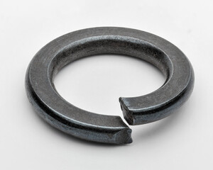 Macro image of black split lock washer isolated on white, symbol of threaded fastening and security. © Adriano