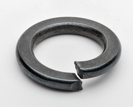 Macro image of black split lock washer isolated on white, symbol of threaded fastening and security.