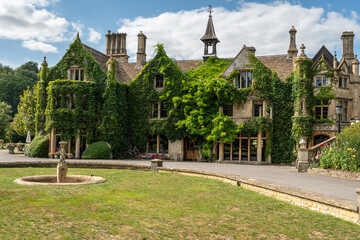 Ivy-covered manor house with a fountain and lawn in the picturesque Castle Combe, Cotswolds, England