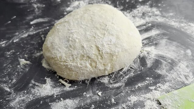 Dough ball on a floured surface gradually changing perspective, showcasing texture and shape in a kitchen setting with baking tools nearby
