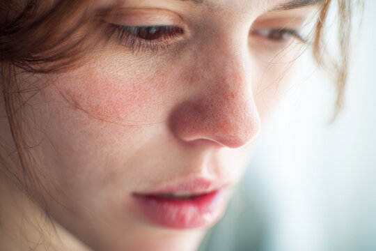 Woman face close up natural skin freckles soft light thoughtful expression beauty young adult healthy complexion emotional serene mood