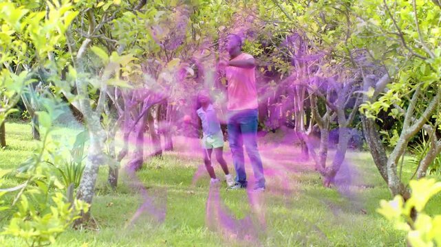 Father guiding daughter in orchard pointing up teaching girl lifting orange toy with purple overlay
