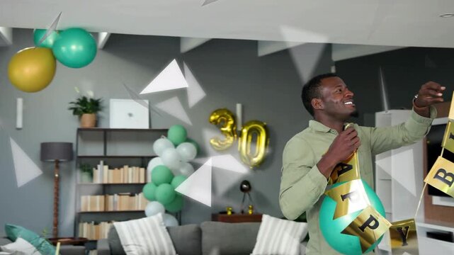 Vertical video: Hanging man in green top aligning banner home while partner bringing gold30 balloon