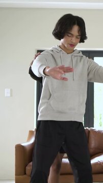 Vertical video: Stepping woman helping man into squat by couch for form, stepping right, copy space