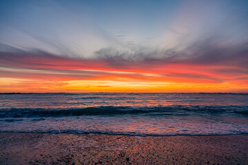 Fototapeta premium Dramatic Golden sunset over tranquil beach, waves lashing the pebble coastline