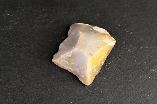Close-up of a rough, unpolished piece of chert stone with translucent yellow and purple hues