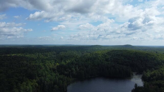 Aerial over the expansive wilderness of crown land located in the Tory Hill area of Haliburton Highlands East, in southern Ontario, Canada. Flying on a shadowy overcast, late summer afternoon.