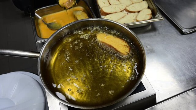 Chef deep frying spanish torrijas dessert in hot oil