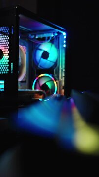 Vertical video. Dark room, gaming computer with multicolored lighting. Camera focus shifts from the keyboard into the distance on the PC.