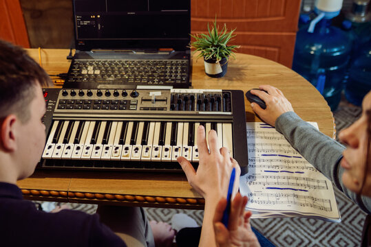 Young Student Learning Piano with Teacher and MIDI Controller in Home Studio