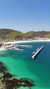 Vertical aerial drone view of emerald green and deep blue ocean with sandy beach in Japan 10