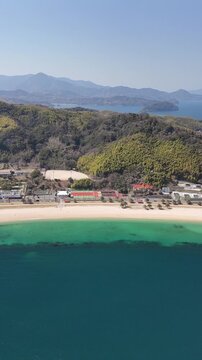 Vertical aerial drone view of emerald green and deep blue ocean with sandy beach in Japan 03