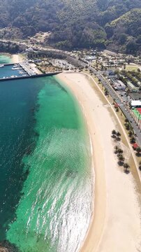 Vertical aerial drone view of emerald green and deep blue ocean with sandy beach in Japan 05