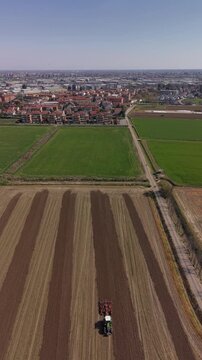 Farmland under Sky: Witness the beauty of agriculture from above, where a tractor carves neat rows across the fertile earth, a testament to industry and the nurturing power of the environment. 
