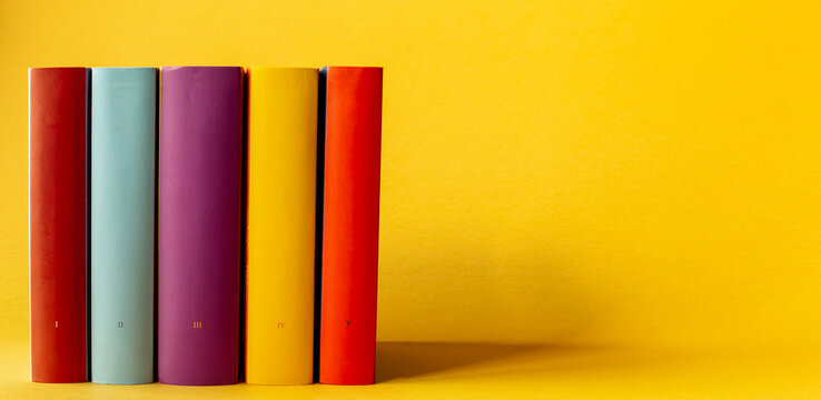 Five books with small roman numerals on their spines on a yellow background with space for additional content.