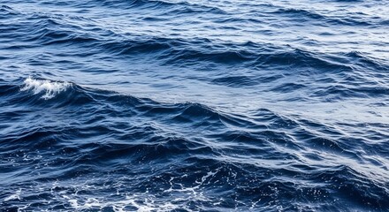 Obraz premium Deep blue ocean water with rolling waves and sea foam.