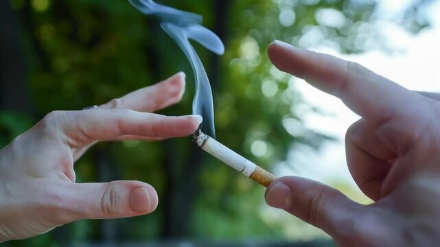 Hands crush a smouldering cigarette against a backdrop of blurred greenery, symbolising the act of quitting smoking and providing a powerful visual backdrop for campaigns to combat tobacco addiction a