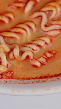 Closeup of fiery ramen in broth. Overhead shot of spicy noodle soup with oil droplets. Glistening instant ramen noodles immersed in vibrant orangered soup with steam