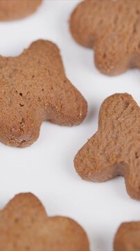 Festive cookies on plain background. Closeup of baked gingerbread treats with warm lighting. Detailed view of holiday gingerbread pastries arranged in repeating pattern