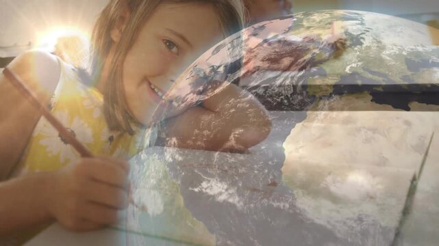 Girl holding pencil, writing on paper, globe fading in and drawing boy into education frame