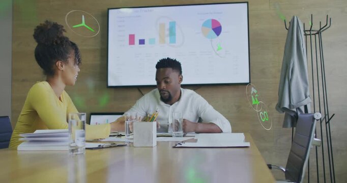 Vertical video: Woman pointing papers and man reviewing, causing eco icons covering meeting charts