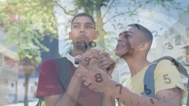 Vertical video: Left guy lifting wrap to mouth causing right pal leaning to taste on sidewalk clock