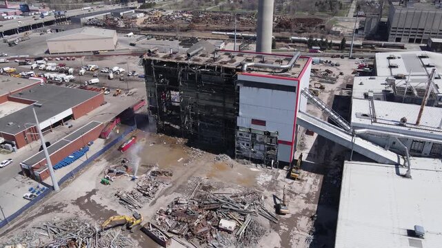Industrial building demolition with excavator and water spray at construction site aerial view