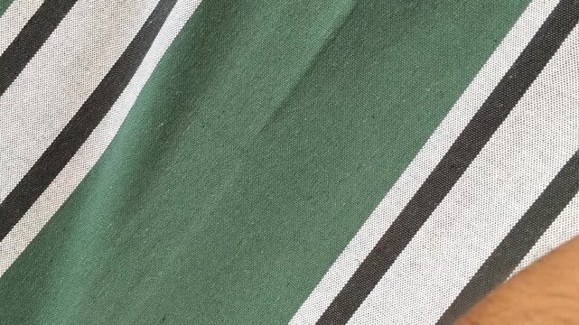 Traditional textile business person hand touch striped cotton cloth fabric surface for checking or examine material quality. Vintage and old style fashion industry cloth design concept.