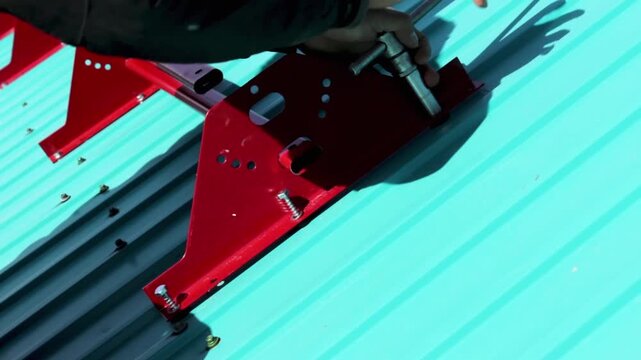 A construction worker is installing a snow holder on the roof. Close-up video.