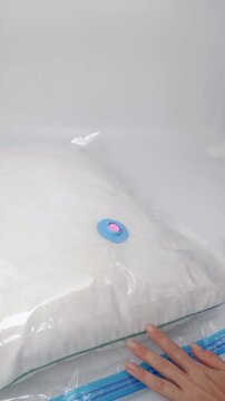 Women's hands open the valve on the bag and screw in the pump to pump out the air