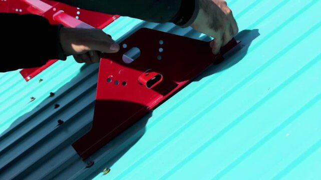 A construction worker installs a snow holder on the roof. Close-up video.