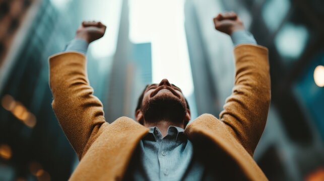 A man raises his arms high in a beautiful urban setting, expressing joy and victory, symbolizing success and accomplishment against a backdrop of skyscrapers.
