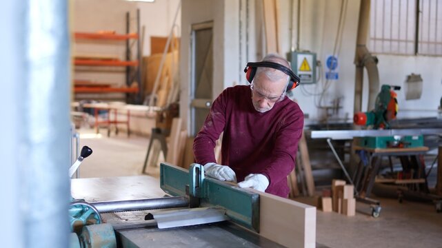 Senior craftsman working with wood planer in workshop