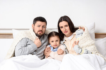 Fototapeta premium Frozen family under blankets with lack of heating in bedroom