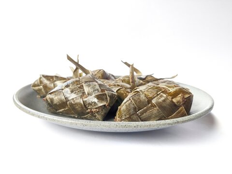 Traditional Indonesian Ketupat Rice Cakes in Woven Palm Leaves Isolated on White
