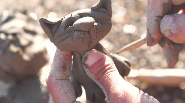 Clay sculpting cat, hands create a charming small feline figurine from mud, craftsmanship and creativity outdoor activity
