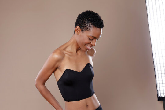 Smiling black woman with short hair posing in professional photo studio with lighting equipment